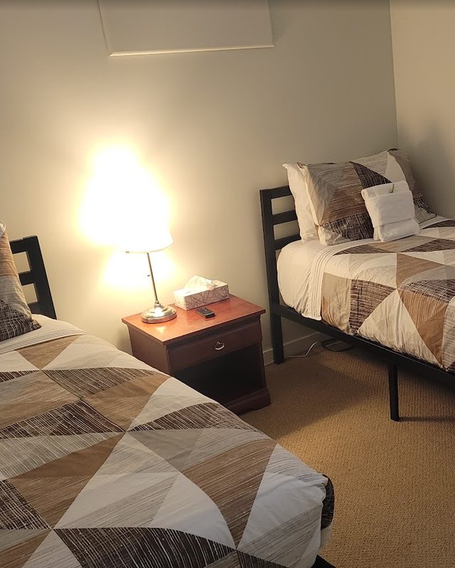 Same Airbnb bedroom after turnover: beds made with fresh linens and towels for the next guest