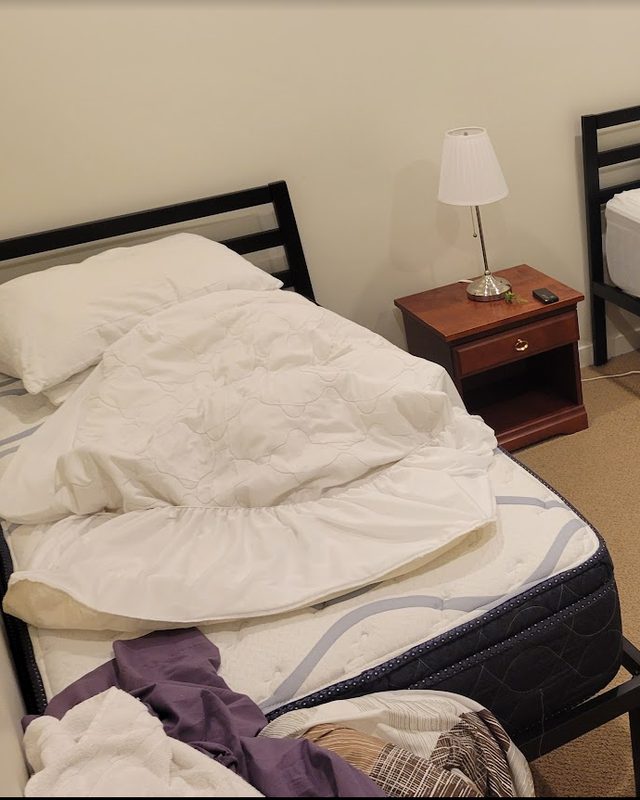 Airbnb bedroom right after guest check-out: beds unmade and used linens piled up
