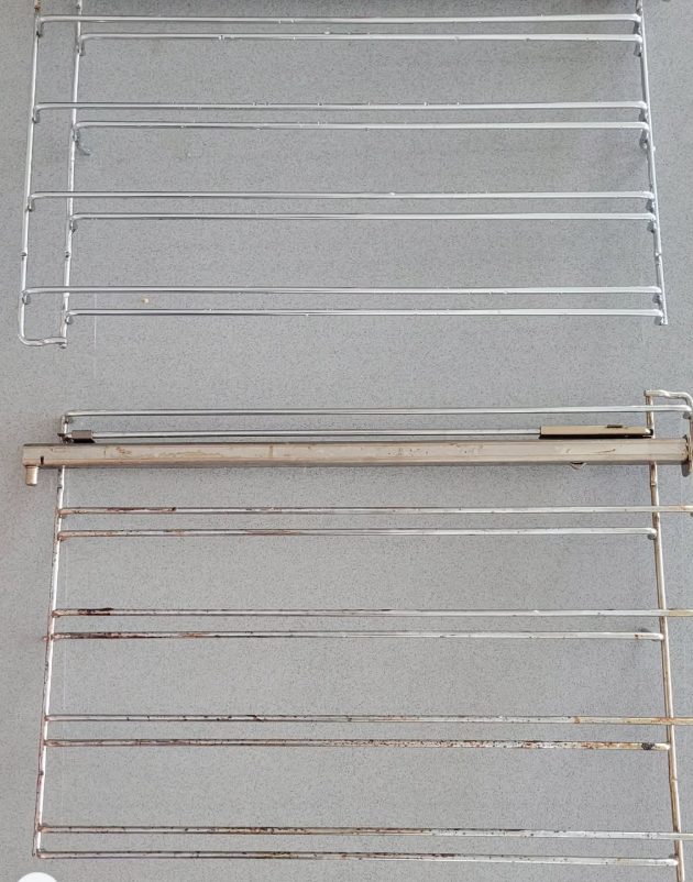 Two oven racks side by side: the top one cleaned and shiny, the bottom one still covered in burnt grease