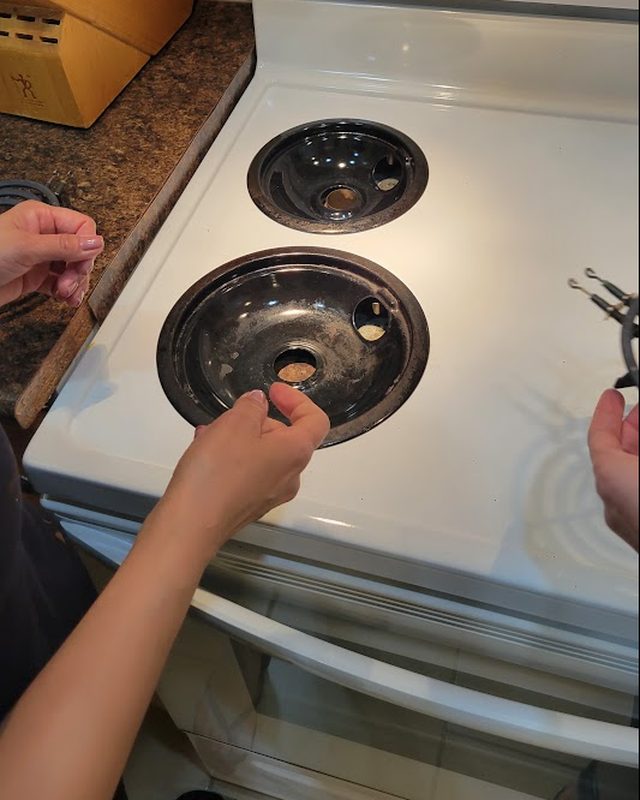 Cleaner removing stovetop drip pans for cleaning